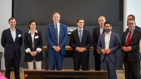 Mehrere Personen stehen in einem Raum und schauen alle in die Kamera