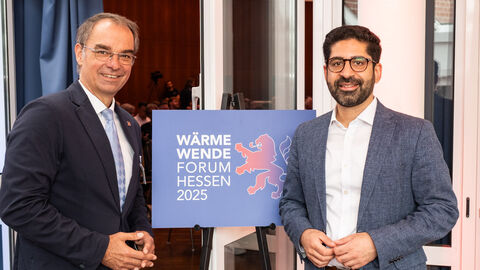 Zwei Männer stehen vor einem Schild 