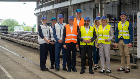 Besuch beim Unternehmen Voestalpine Mehrere Personen in orangenen Warnwesten stehen in einer Halle