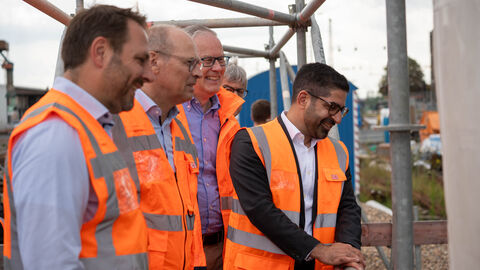 Besuch der Bahnhofsbaustelle Gelnhausen Mehrere Personen in orangenen Warnwesten stehen auf einem Gerüst