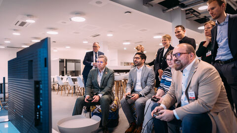 Mehrere Personen sitzen vor einem Bildschirm und spielen Videospiele