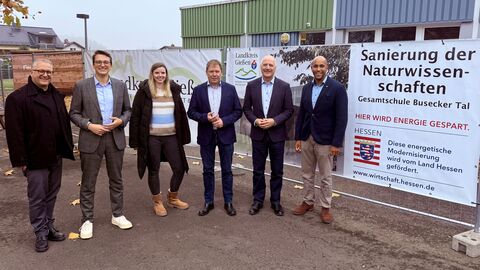 Mehrere Personen stehen vor einem Bauzaun