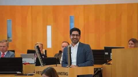 Ein Mann steht an einem Pult in einem Plenarsaal