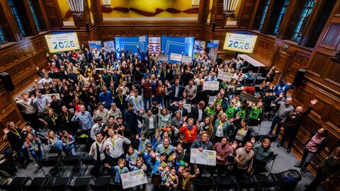 Mehrere Personen stehen in einem großen Raum und winken in die Kamera