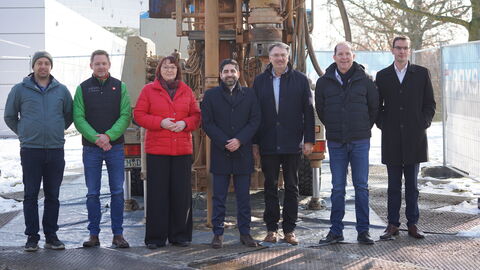 Mehrere Personen stehen vor einem großen Geothermie-Bohrer