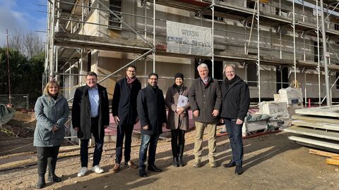 Mehrere Personen stehen vor einem Rohbau